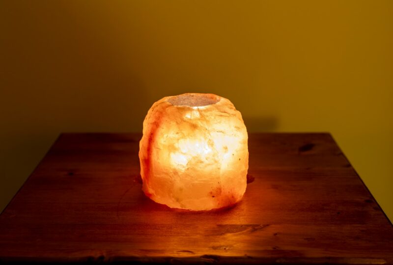 Upaljena lampa od kamene soli na drvenom stolu