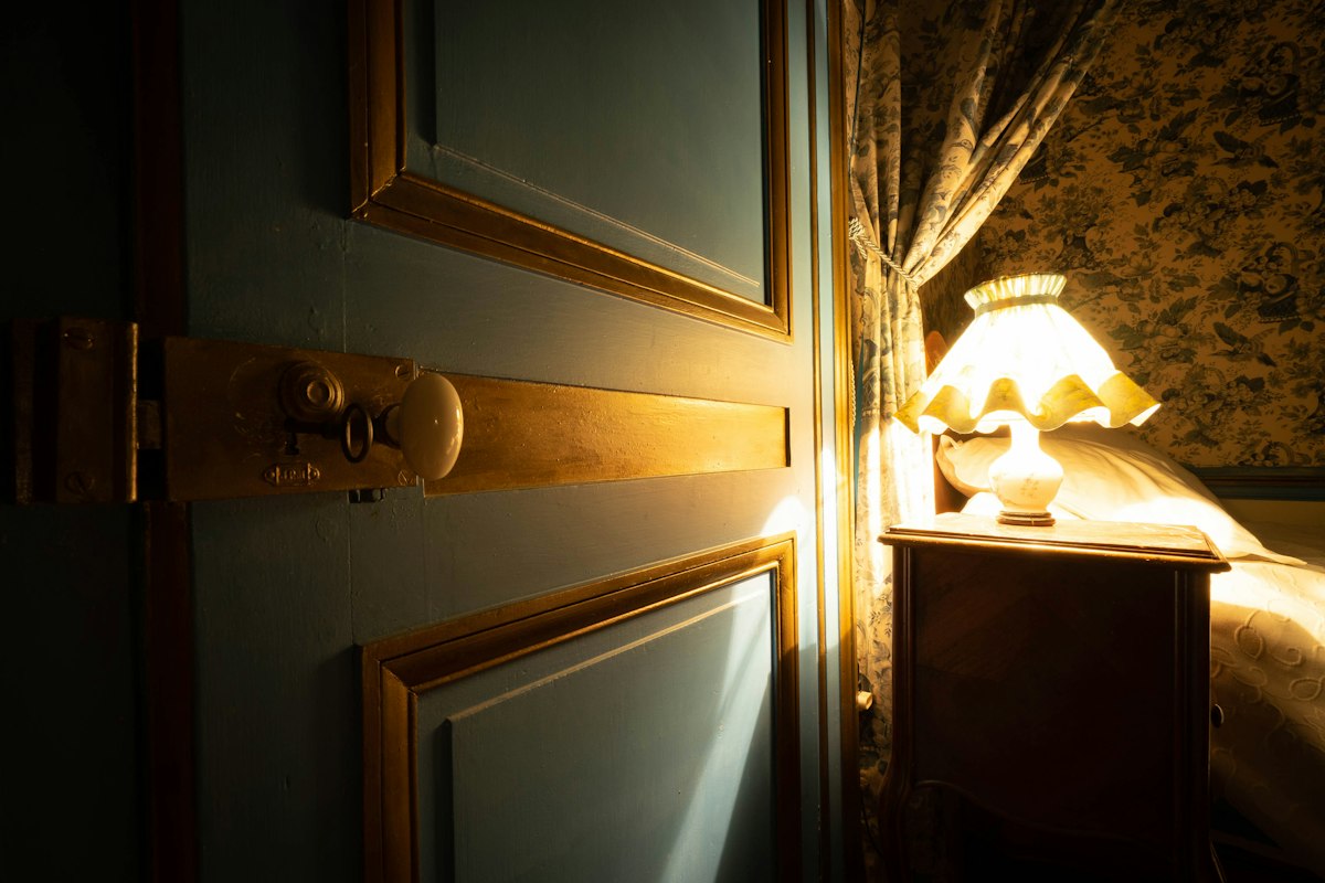 Prigu&scaron;ena lampa na noćnom stočiću u zamračenoj sobi